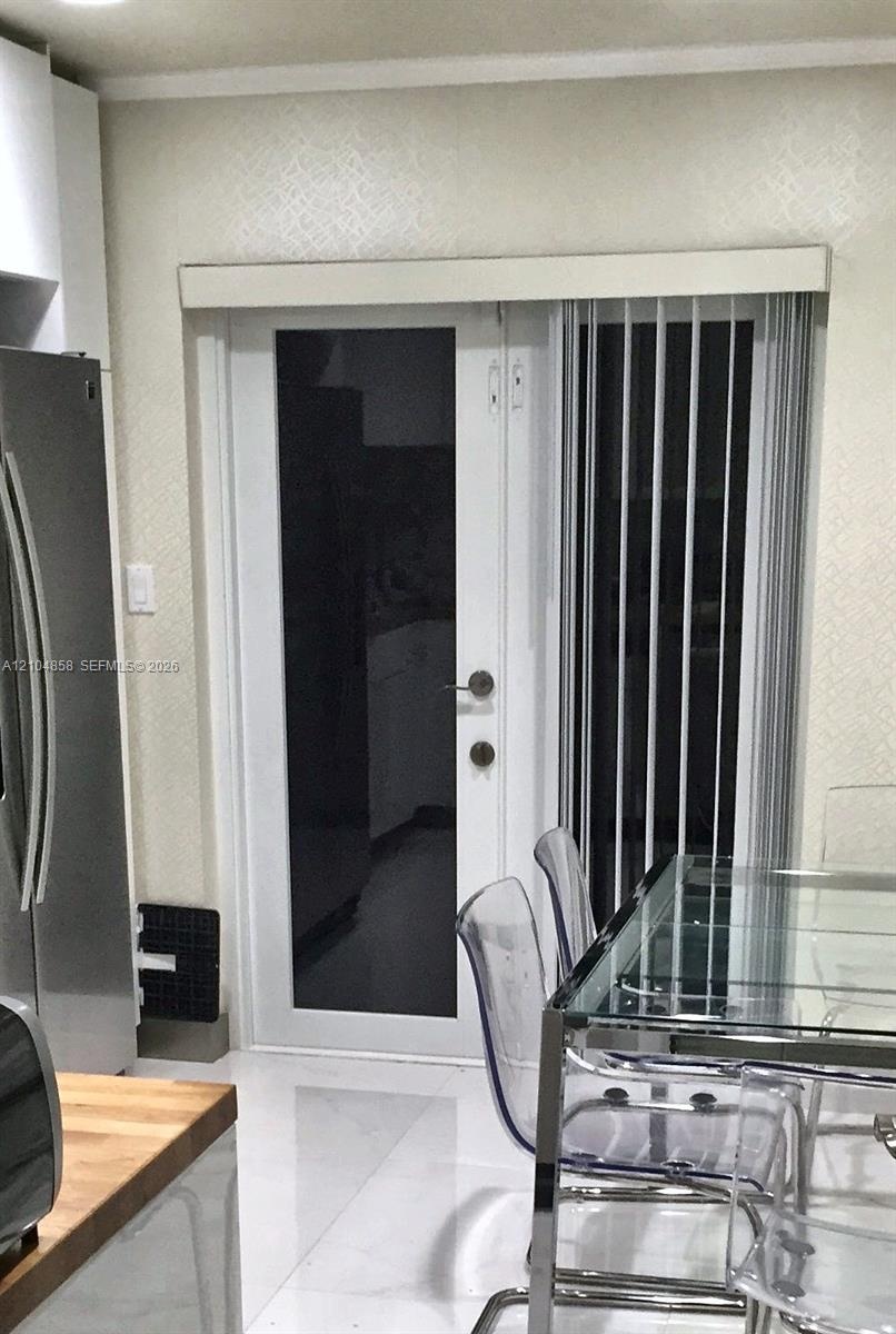 Full-light glass exterior door featuring a white frame and brushed metal hardware, complemented by white vertical blinds and neutral textured wall fin
