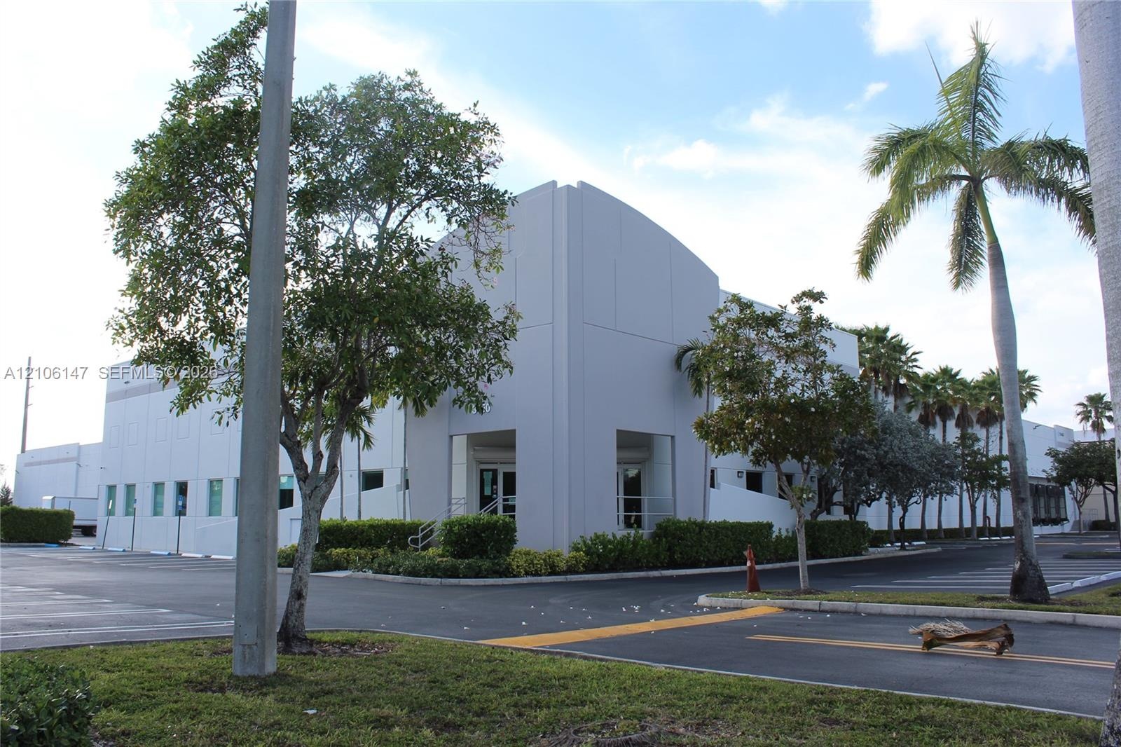 Commercial industrial building featuring a concrete exterior, multi-pane window configuration, and dedicated asphalt parking area