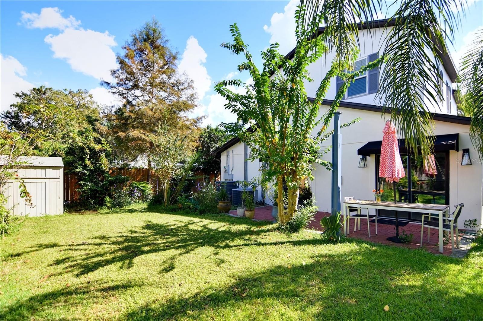 Expansive backyard with mature palms, green lawn, and views of the home's rear exterior.