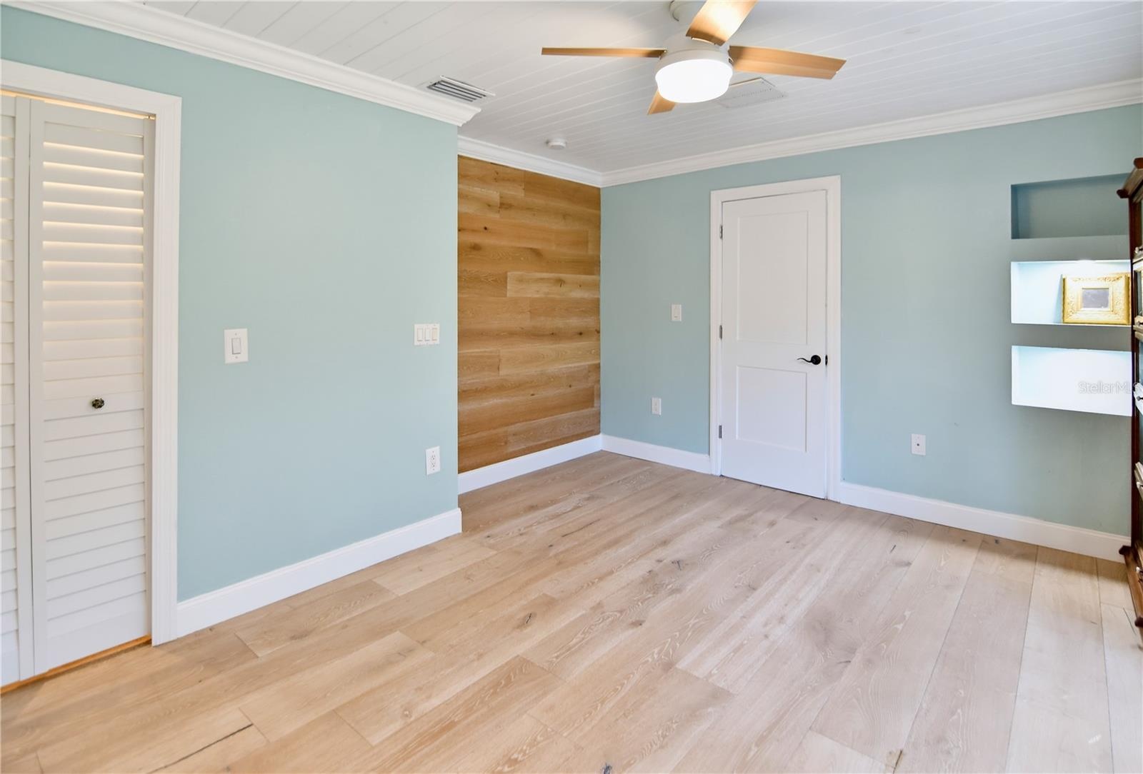 Versatile downstairs bedroom with updated flooring, ceiling fan, and built-in storage.