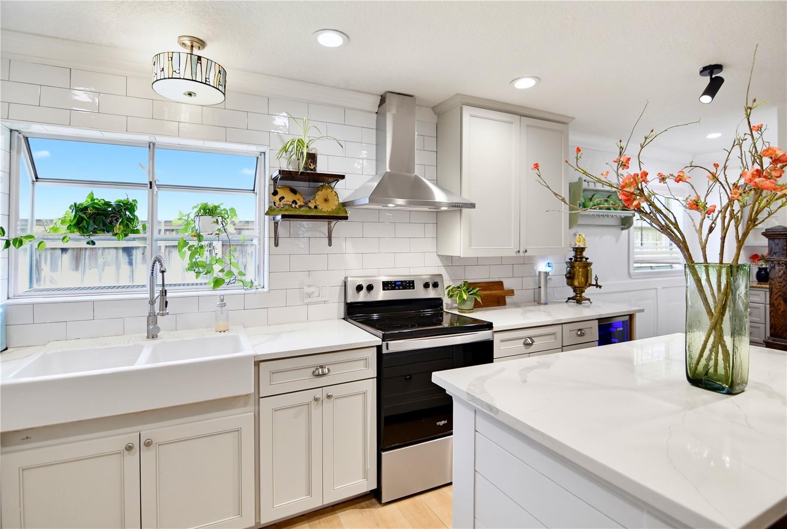 Bright kitchen with farmhouse sink, stainless steel appliances, and attractive cabinetry.