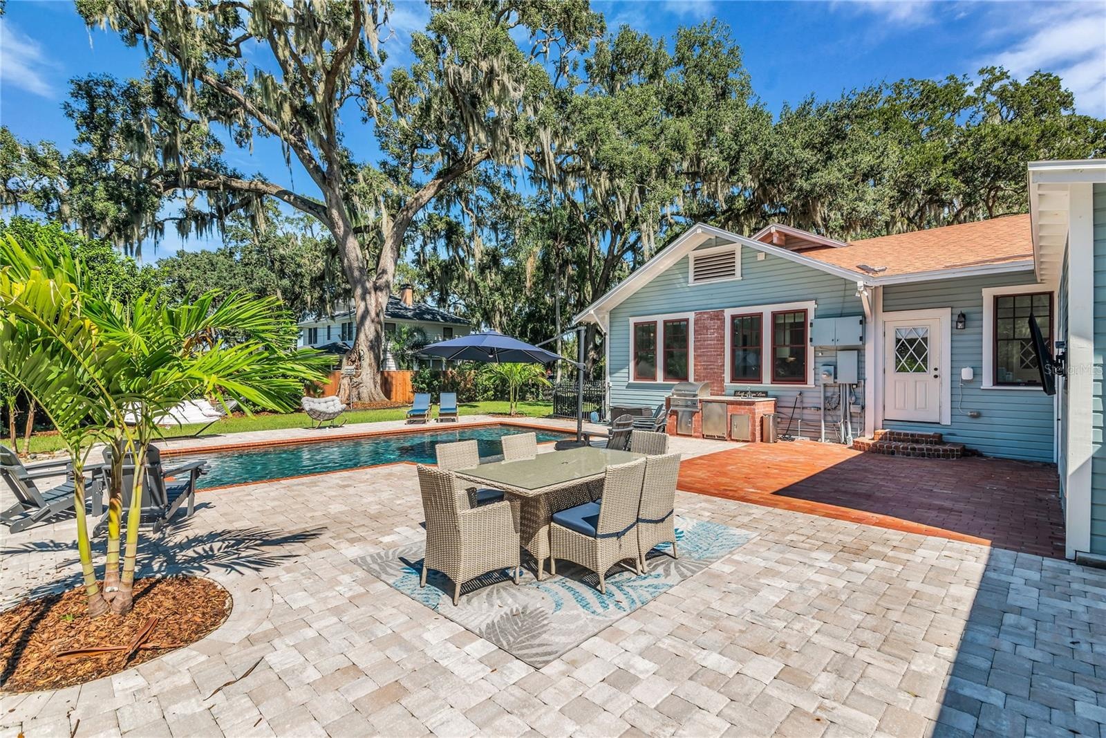 The enormous fully fenced backyard is designed for year-round enjoyment with a gas-heated saltwater sport pool, outdoor kitchen, expansive brick paved