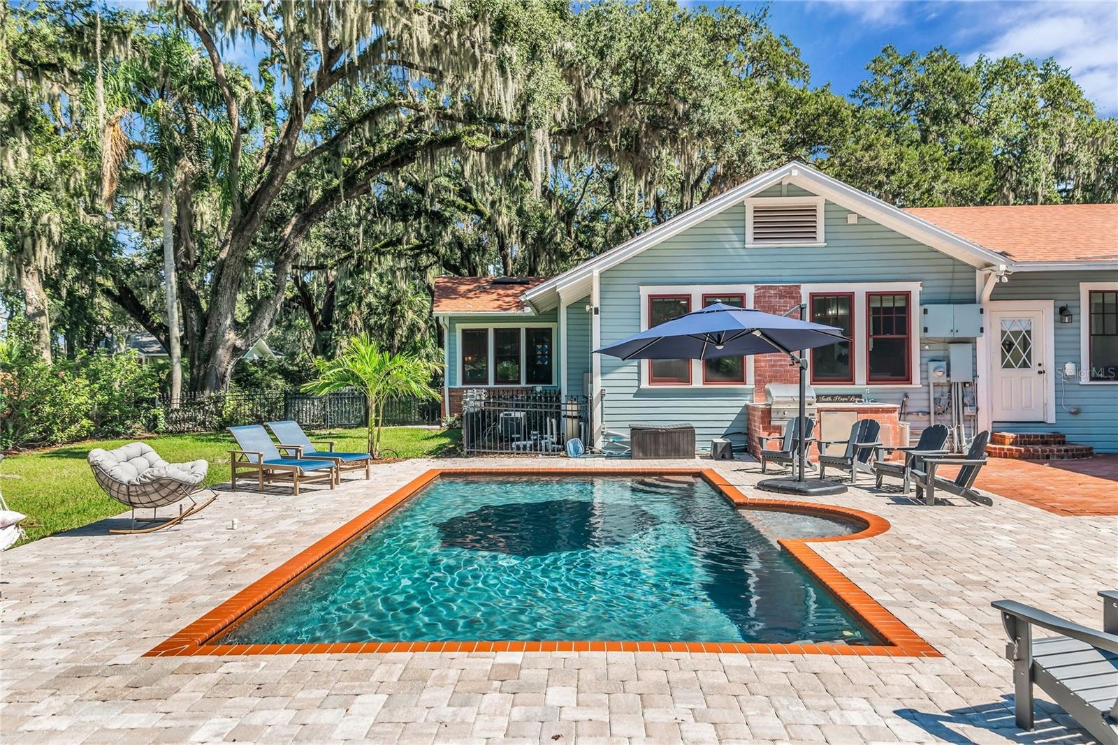The enormous fully fenced backyard is designed for year-round enjoyment with a gas-heated saltwater sport pool, outdoor kitchen, expansive brick paved