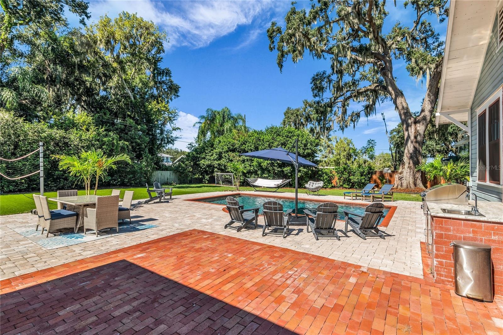 The enormous fully fenced backyard is designed for year-round enjoyment with a gas-heated saltwater sport pool, outdoor kitchen, expansive brick paved