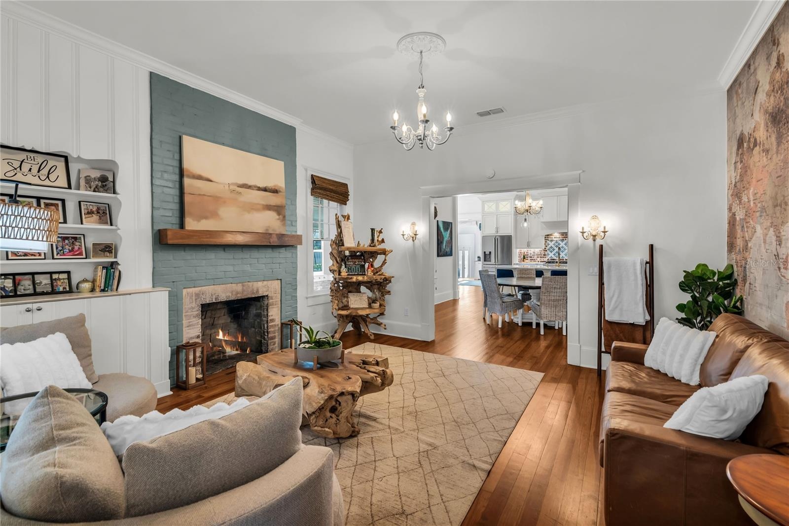 The warm and welcoming Formal Living Room is anchored by a wood-burning brick fireplace accented by a substantial wood mantle and custom painted brick