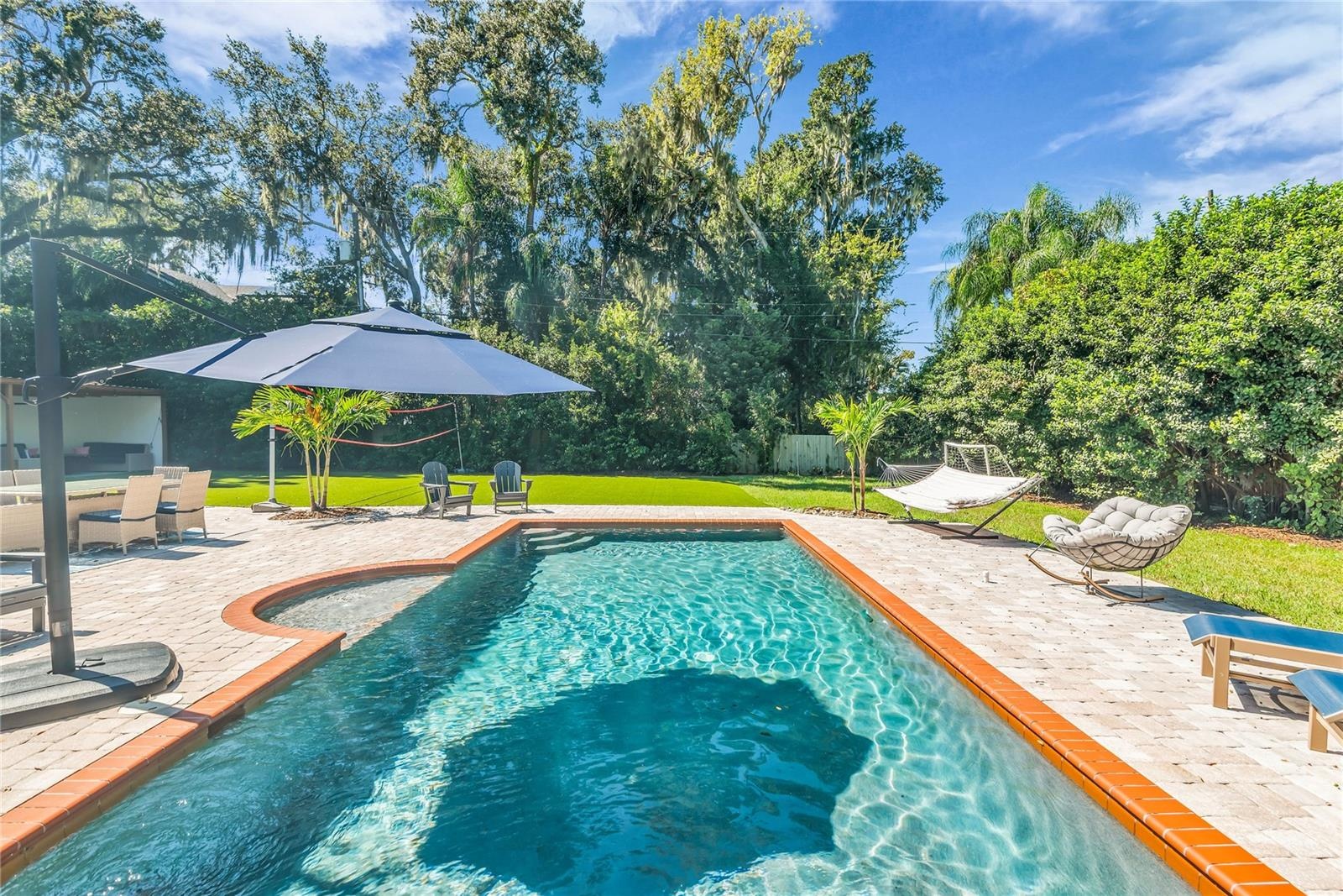 The enormous fully fenced backyard is designed for year-round enjoyment with a gas-heated saltwater sport pool, outdoor kitchen, expansive brick paved