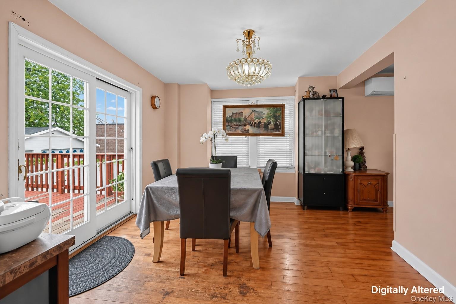 Wood-finish flooring throughout, with a crystal chandelier, and a white-framed glass sliding door leading to an outdoor deck