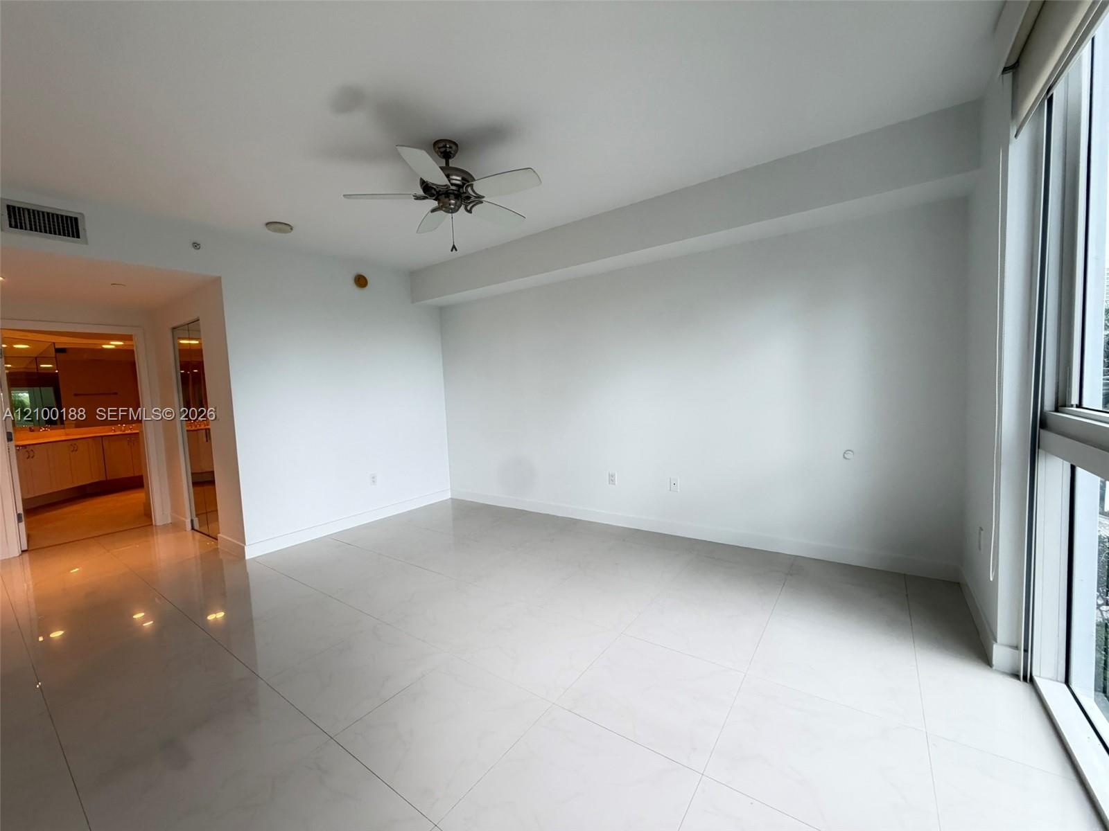 Large-format tile flooring, ceiling fan, and floor-to-ceiling windows