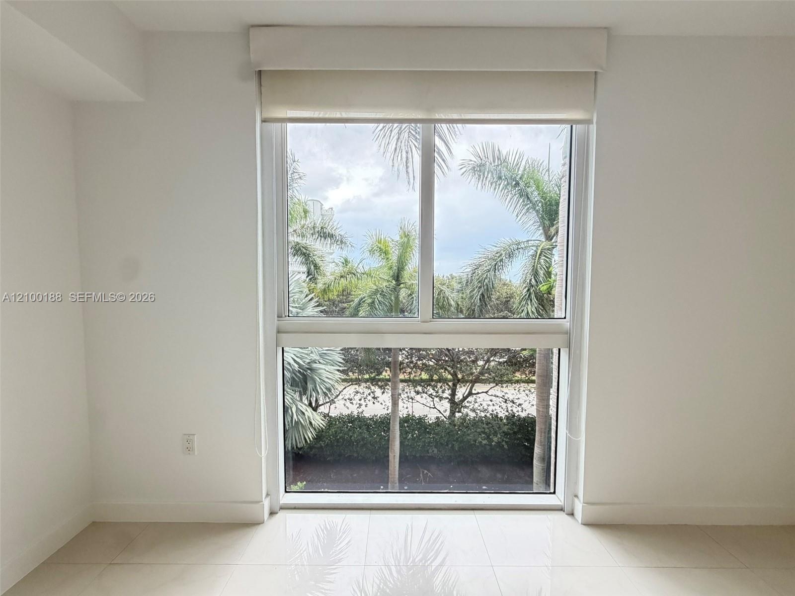 Large rectangular window featuring dual-pane glass, a valance, and a retractable roller shade, complemented by tile flooring and neutral wall finishes