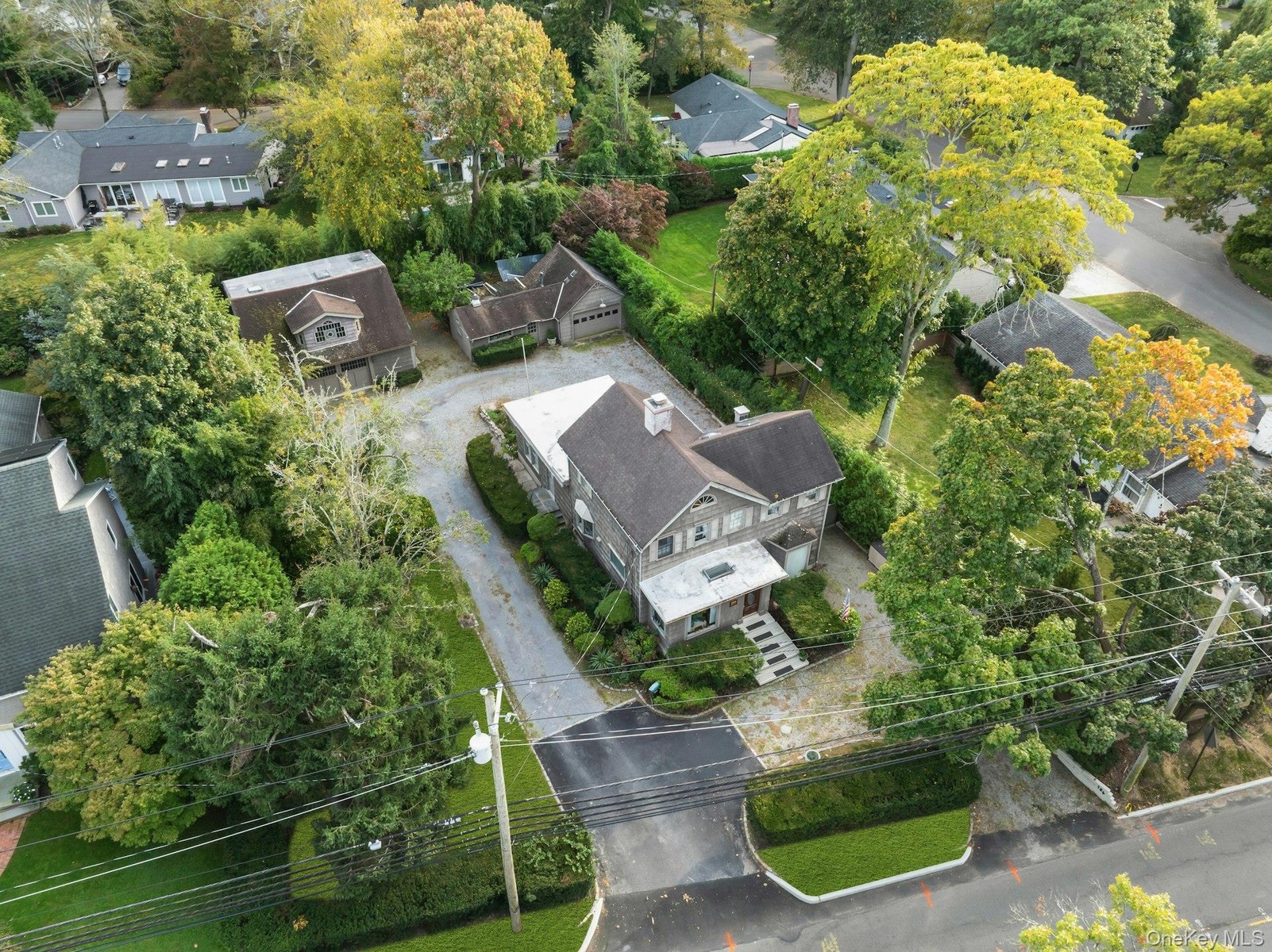 Shingle-sided residence with a covered front porch, stone steps, and a paved driveway
