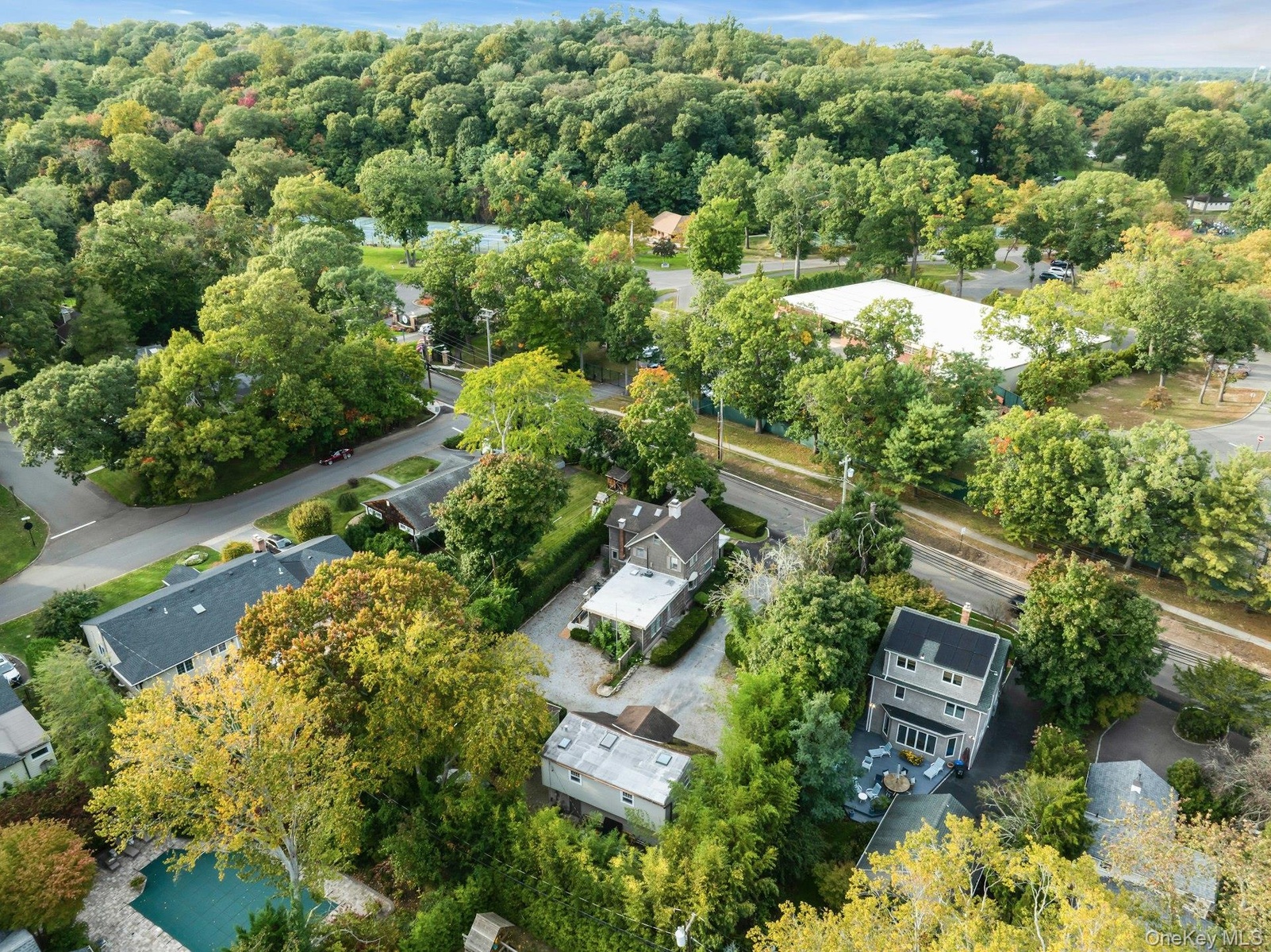Aerial perspective showcasing multiple properties, lush green landscaping, and paved roads