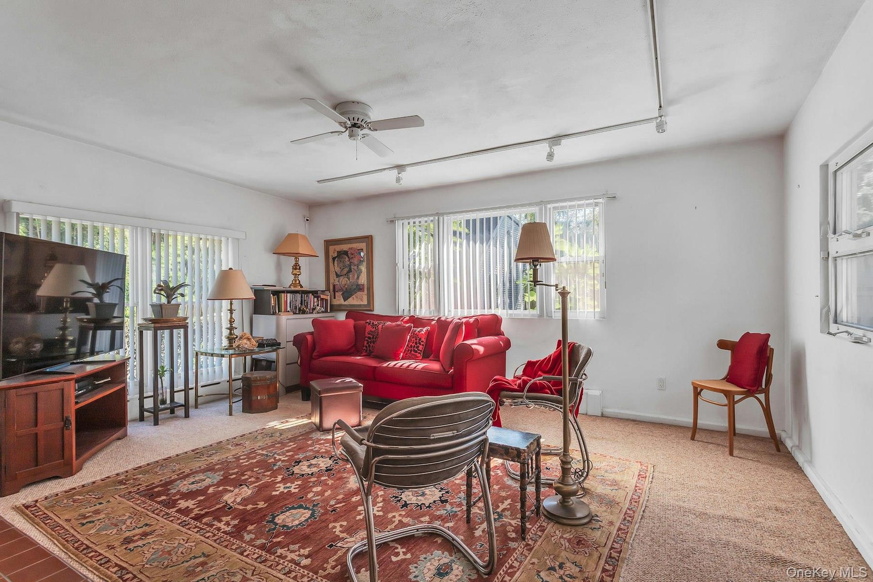 Bright living space featuring multiple windows, carpet flooring, and a ceiling fan