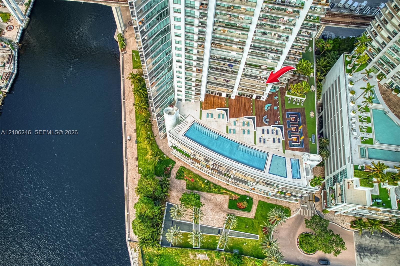 High-rise property featuring an expansive outdoor recreation deck with a multi-level swimming pool, manicured lawn areas, wood-finish decking, and dir