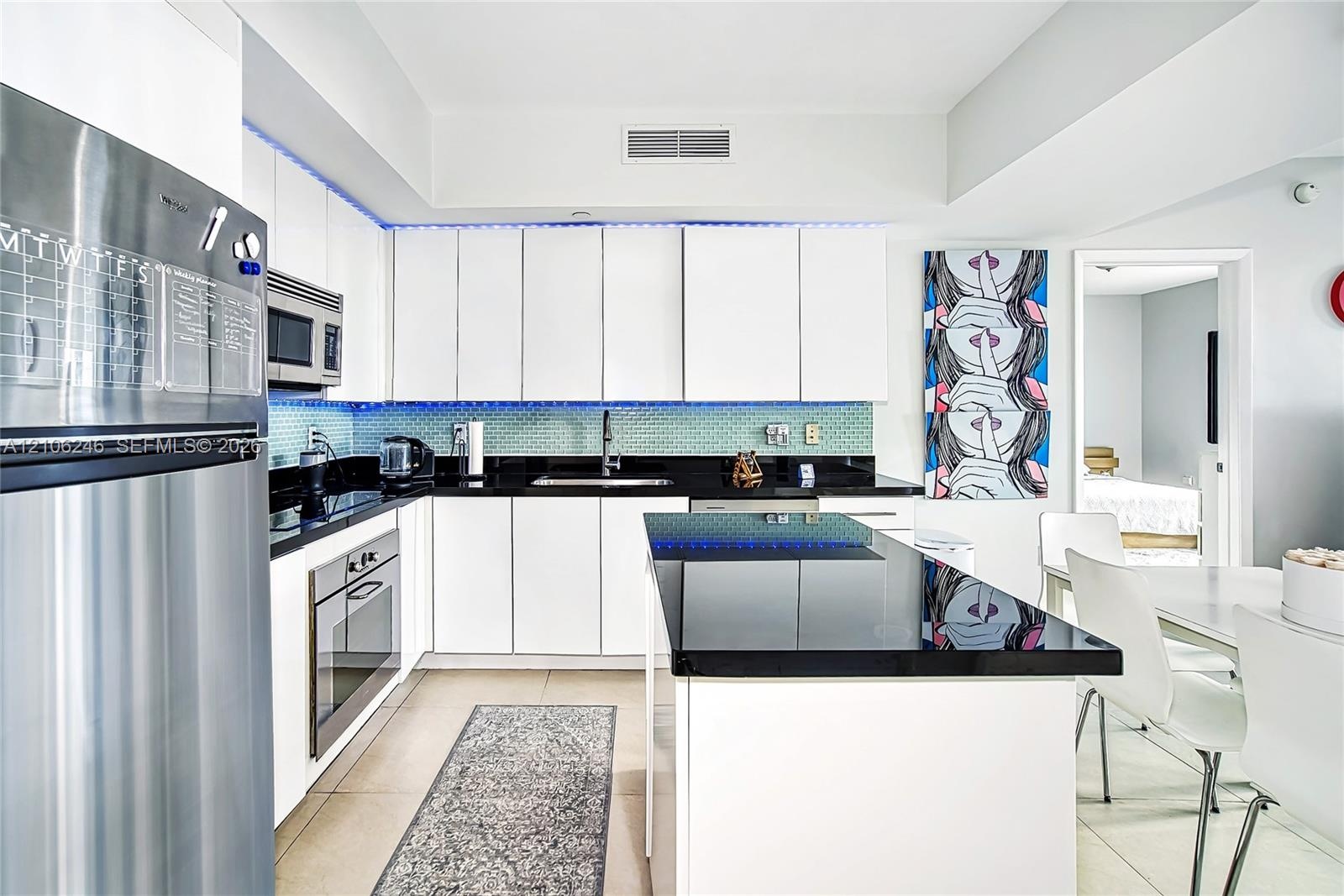 Kitchen featuring white flat-panel cabinetry, a central island with a solid surface countertop, stainless steel appliances, and a tiled backsplash