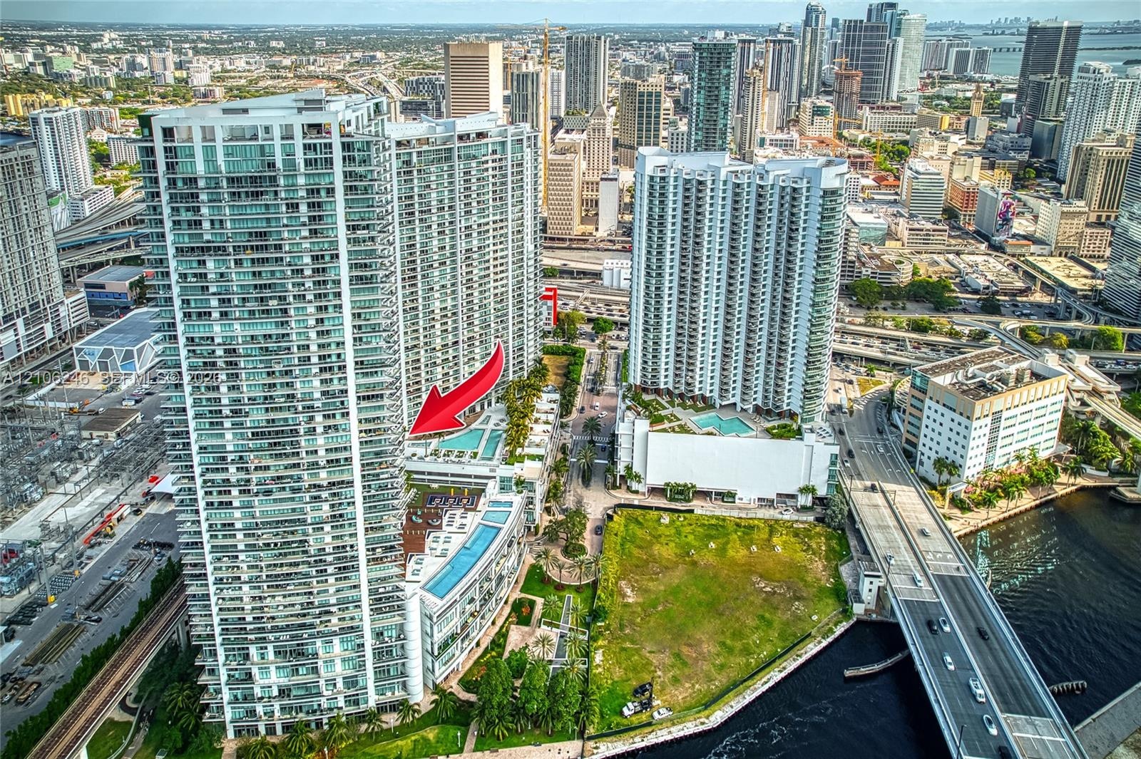 High-rise residential tower featuring a multi-level swimming pool deck, glass balcony railings, floor-to-ceiling windows, and direct urban skyline exp
