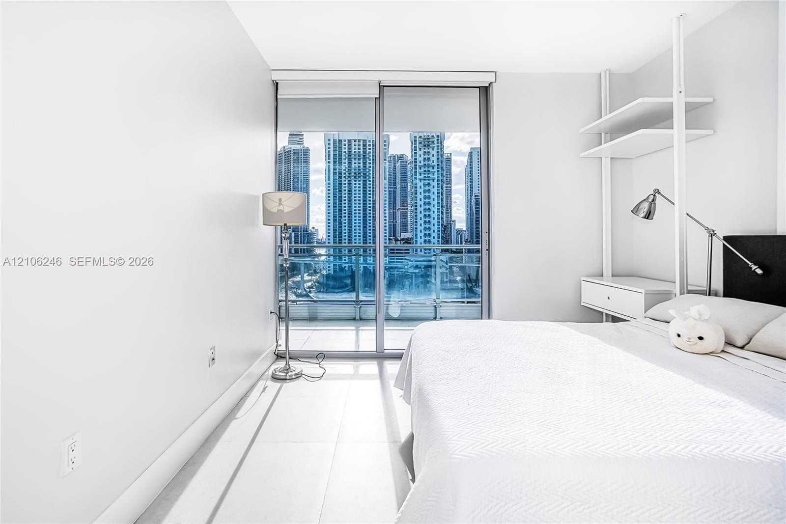 Floor-to-ceiling glass sliding doors, large-format tile flooring, built-in shelving unit with an integrated drawer, and urban skyline backdrop