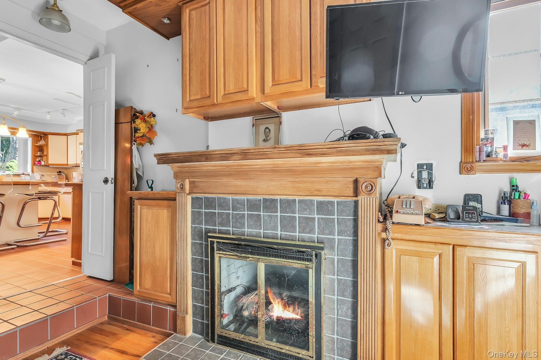 Tile fireplace surround with a wood mantel, wood cabinetry, and wood-finish flooring