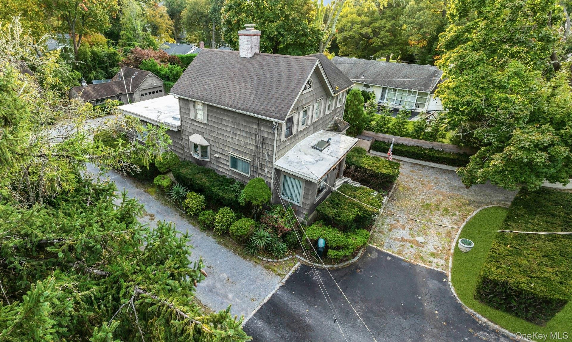 Shingle-sided residence featuring a prominent chimney and bay window
