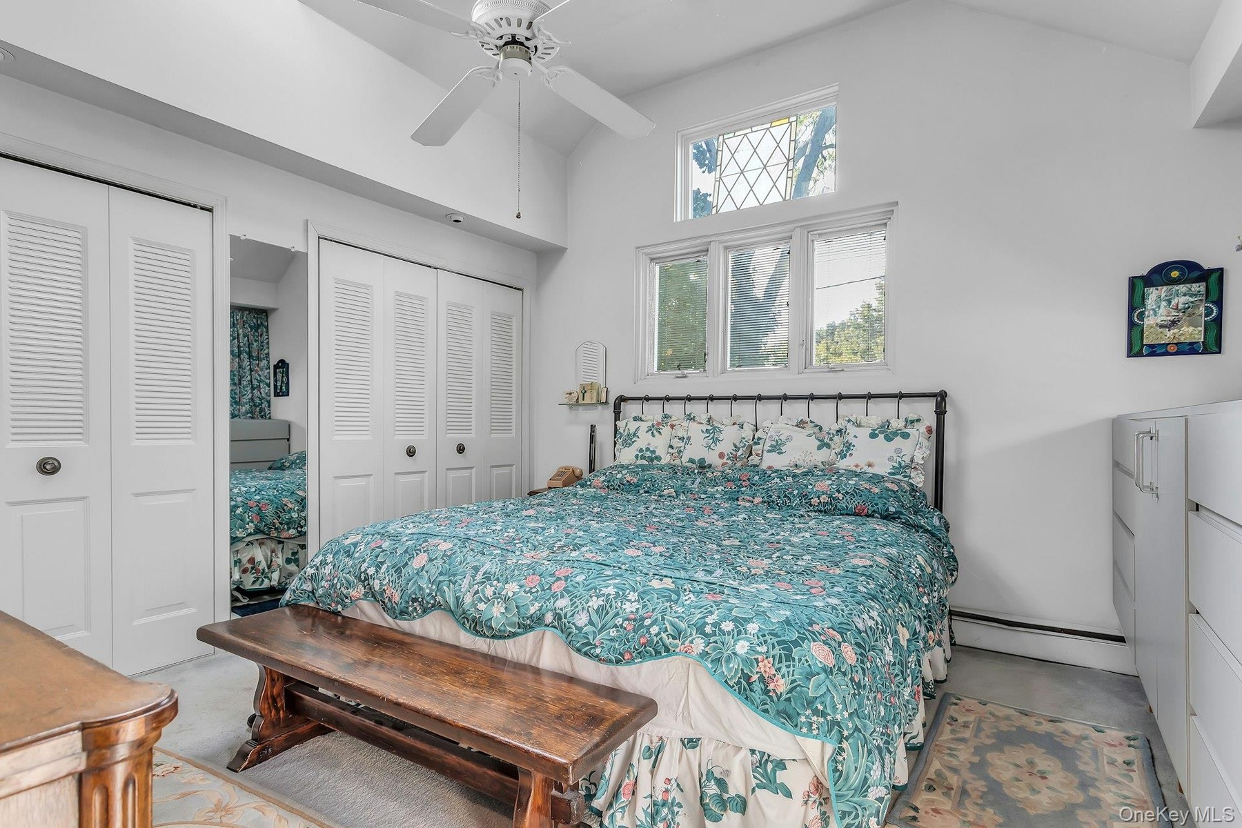 Vaulted ceiling with a ceiling fan, multiple windows with transom, and bi-fold louvered closet doors