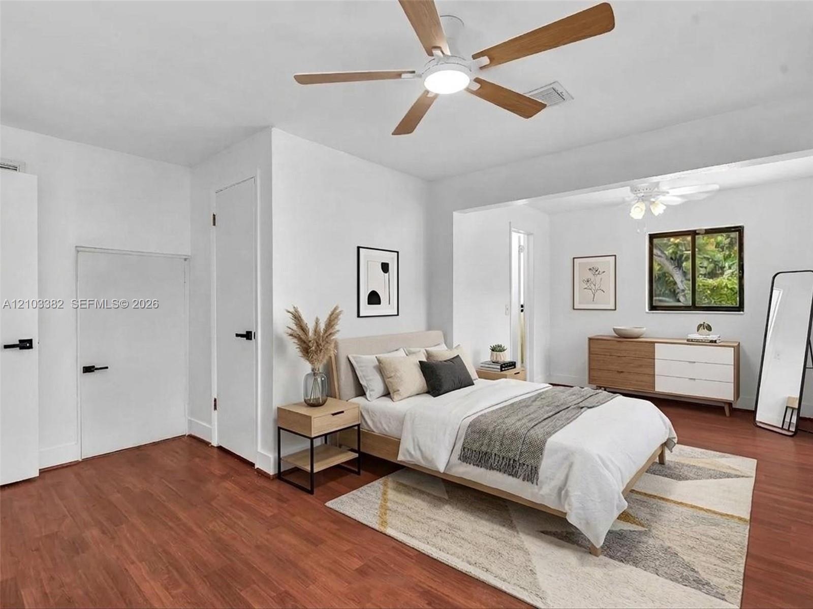 VIRTUAL STAGING. Rear private bedroom featuring walk-in closet, en-suite bath, siting area and wood-finish flooring, white doors with matte black hard