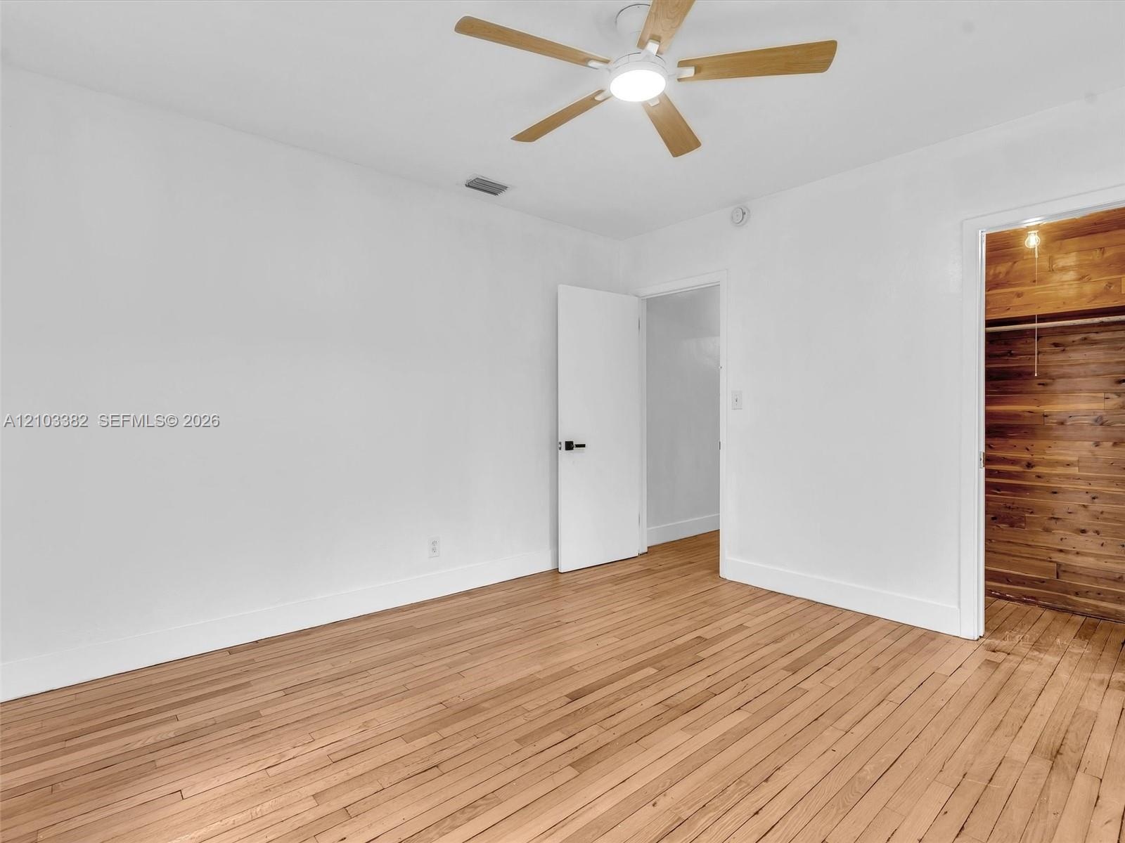 Front east bedroom featuring wood-finish flooring, a ceiling fan with integrated lighting, and a closet finished with wood paneling.House for rent in 