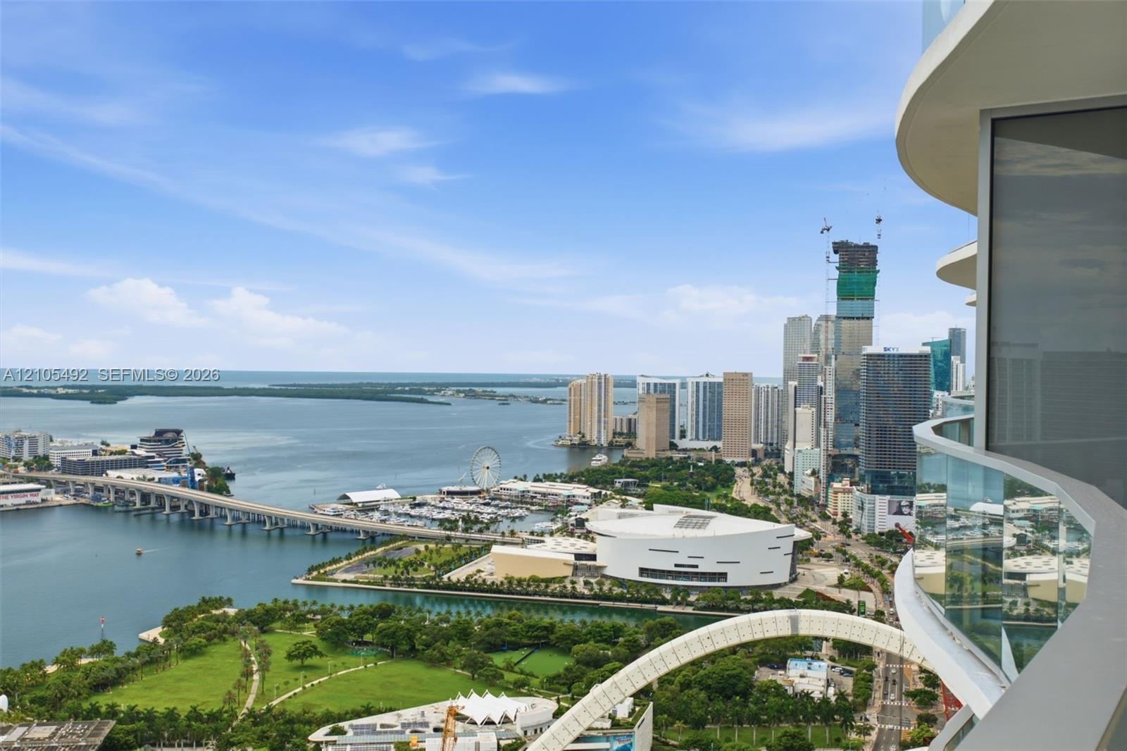 Curved balcony featuring glass railings and expansive water and urban skyline scenery