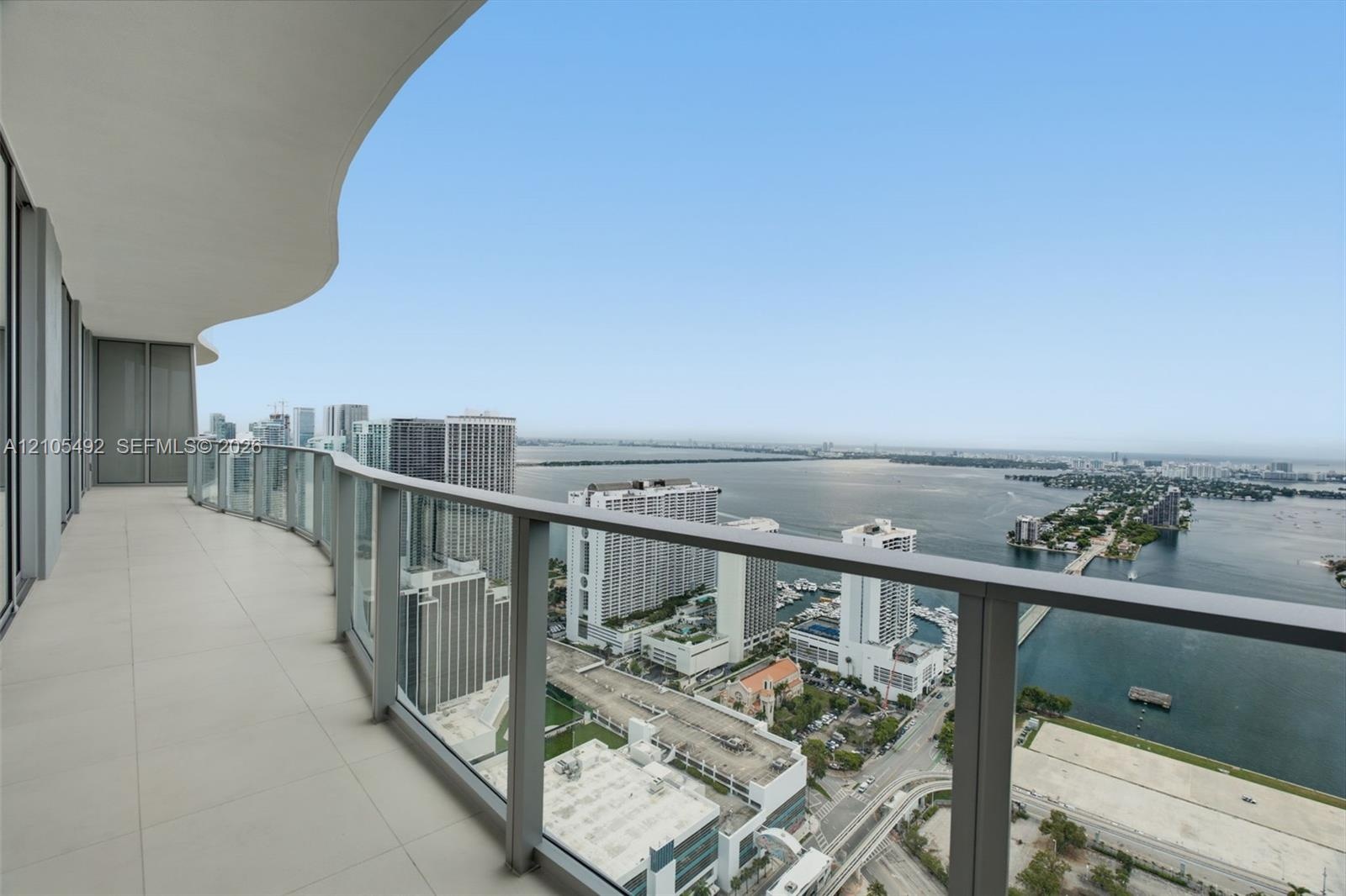 Curved balcony featuring large-format tile flooring and a glass-paneled railing