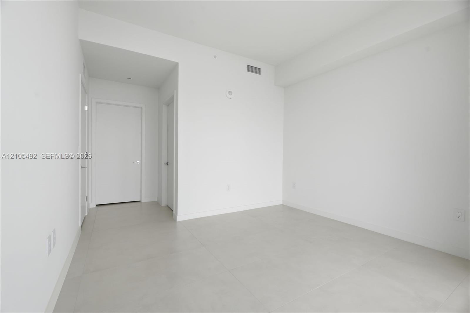 Neutral-toned large-format tile flooring, smooth wall finishes, and solid-core interior doors
