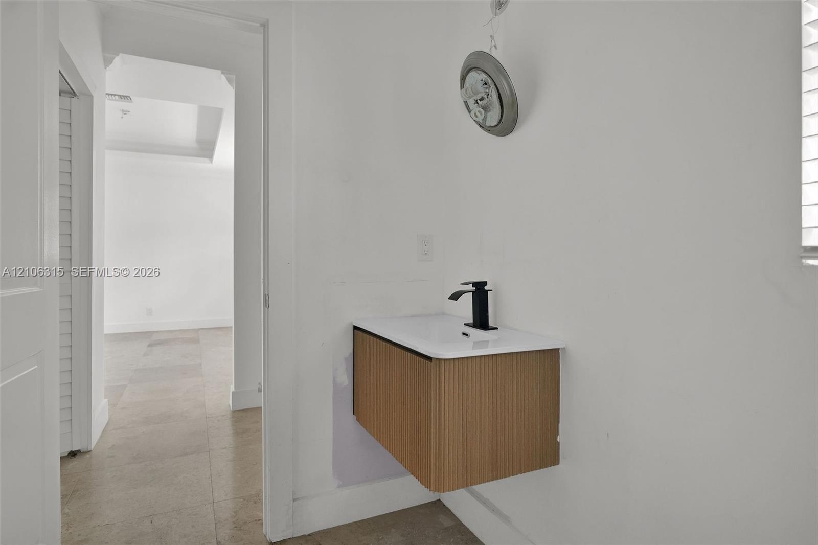 Wall-mounted floating vanity with reeded wood-finish cabinetry, white countertop, and matte black single-handle faucet