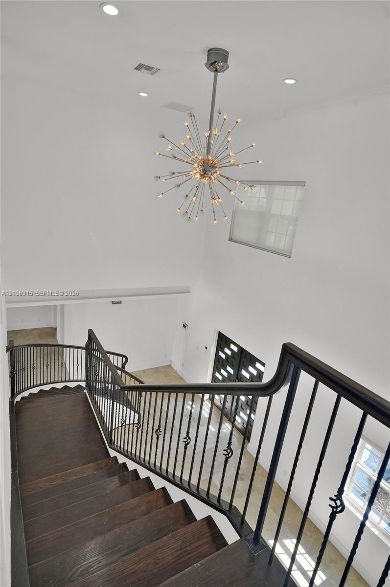 Staircase featuring dark wood-finish treads and a decorative metal railing, highlighted by a multi-point sputnik-style chandelier, recessed lighting, 