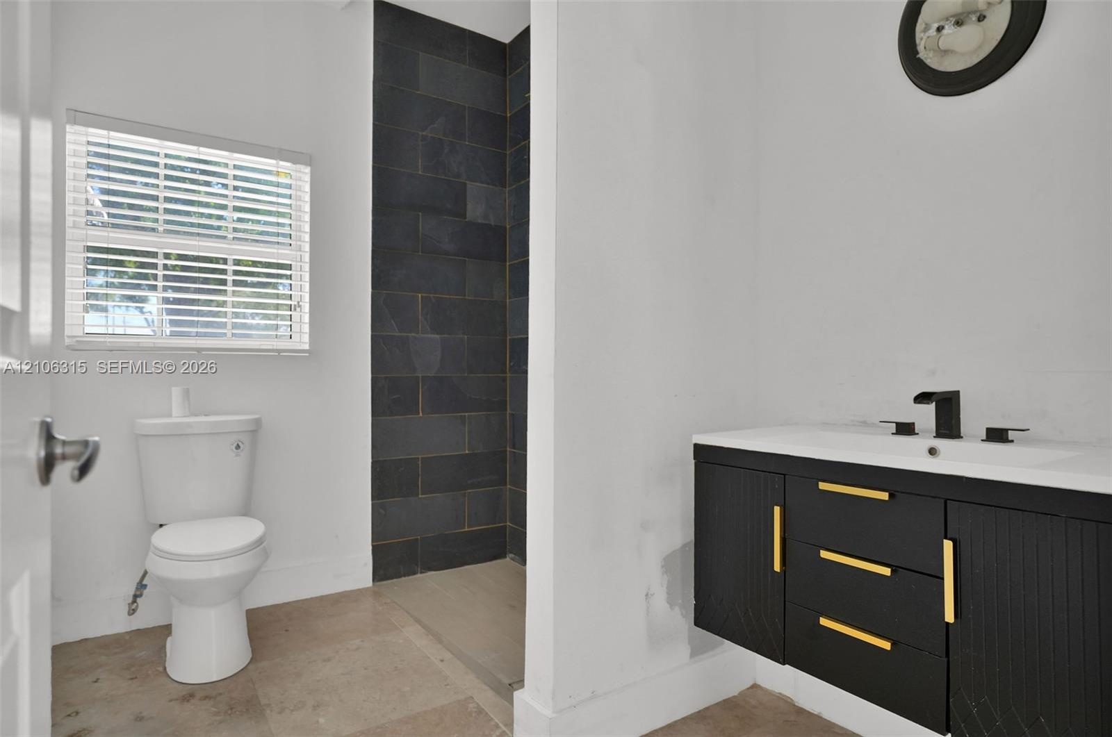 Bathroom featuring a floating vanity with black cabinetry, gold-tone hardware, and a white countertop