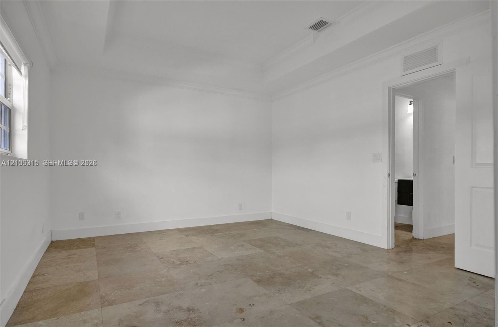 Neutral-toned tile flooring, recessed tray ceiling with crown molding, and a multi-panel door