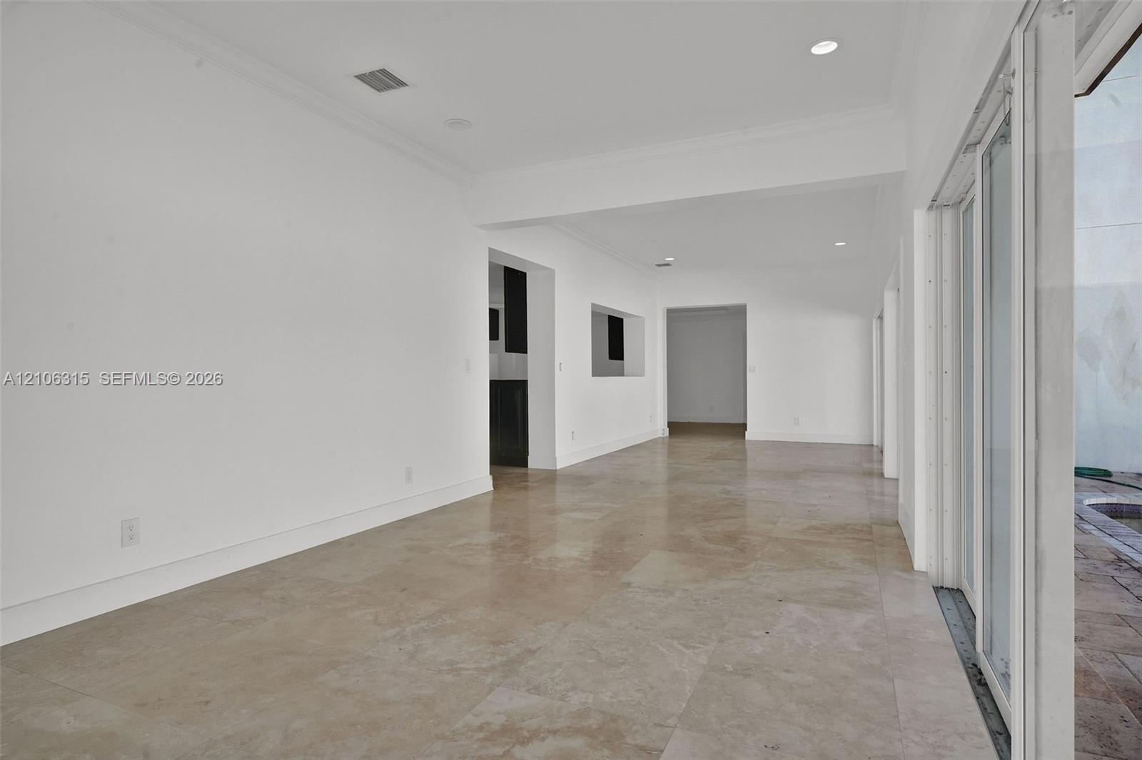 Neutral-toned large-format tile flooring, recessed ceiling lighting, and expansive multi-panel sliding glass door system