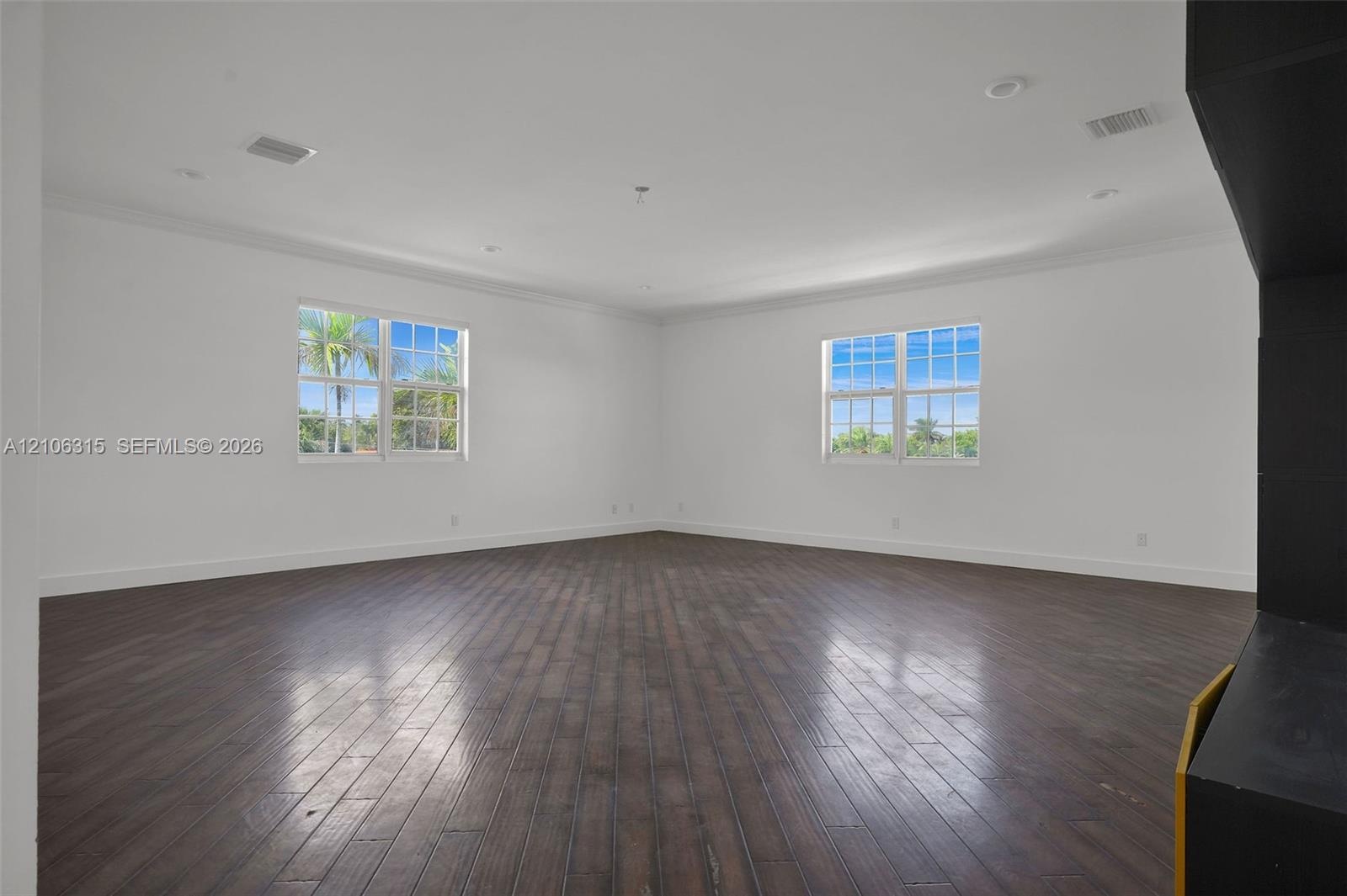 Interior space featuring dark wood-finish flooring, multi-pane windows, recessed lighting, and crown molding