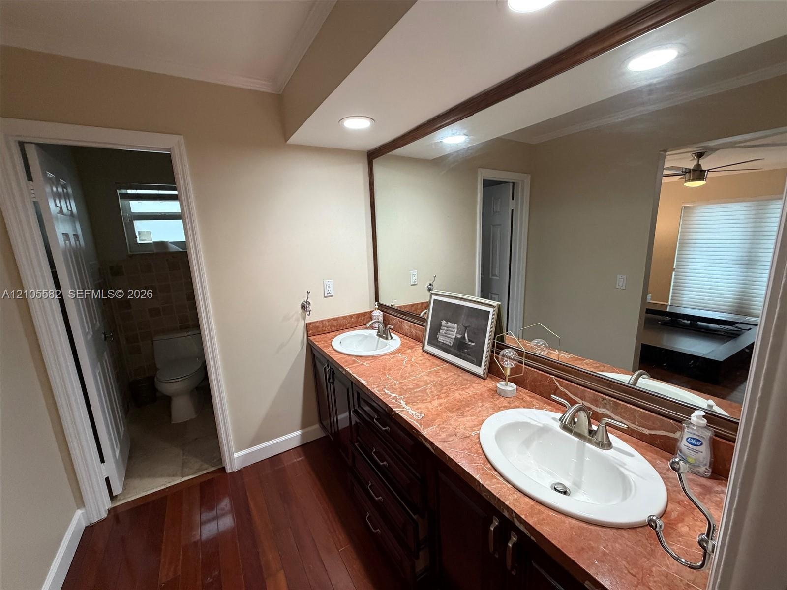 Double vanity with integrated sinks, rich wood-finish cabinetry, and recessed lighting