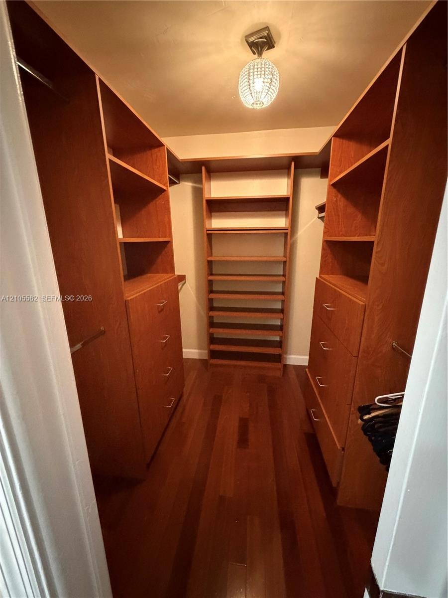 Hardwood flooring complemented by built-in wood-finish cabinetry, integrated shelving, and a decorative ceiling fixture
