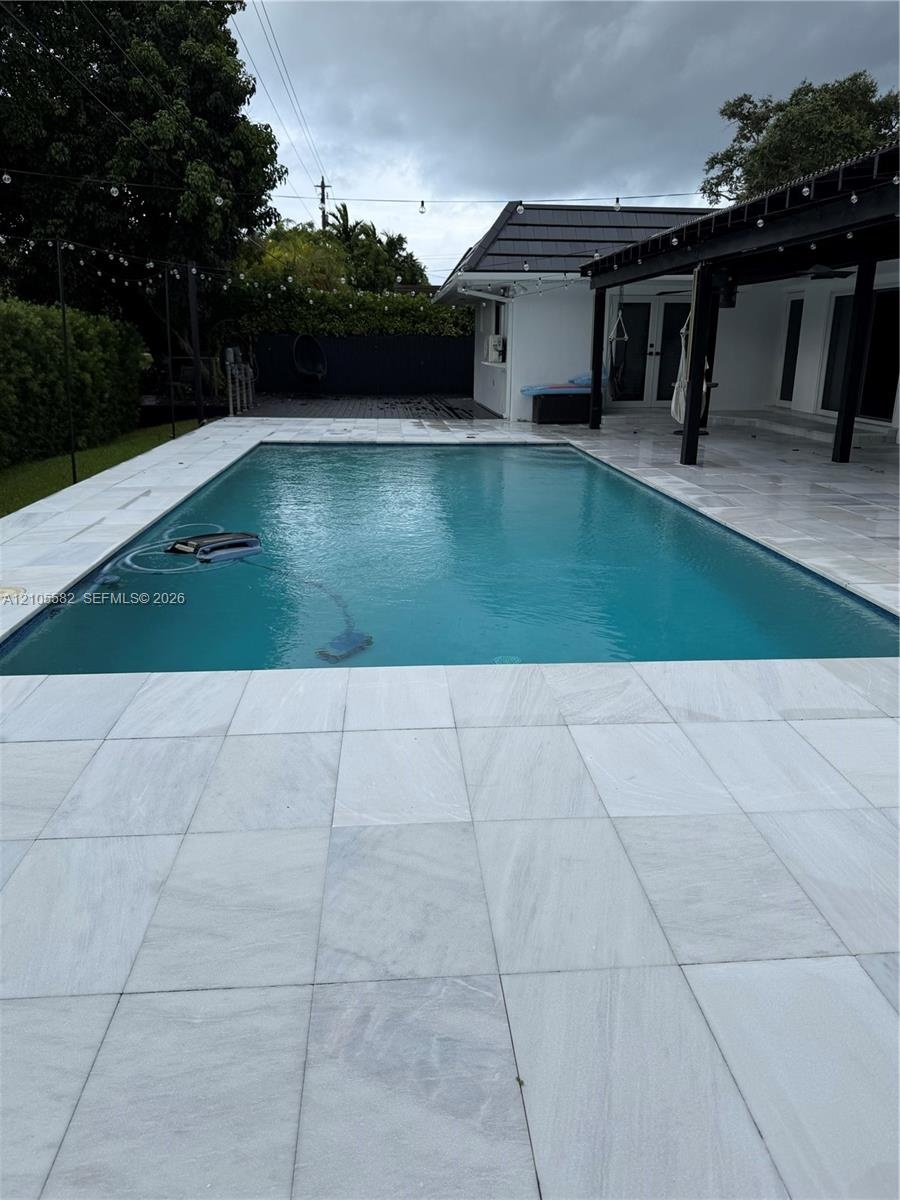 Rectangular swimming pool with light-toned tiled coping and surrounding patio