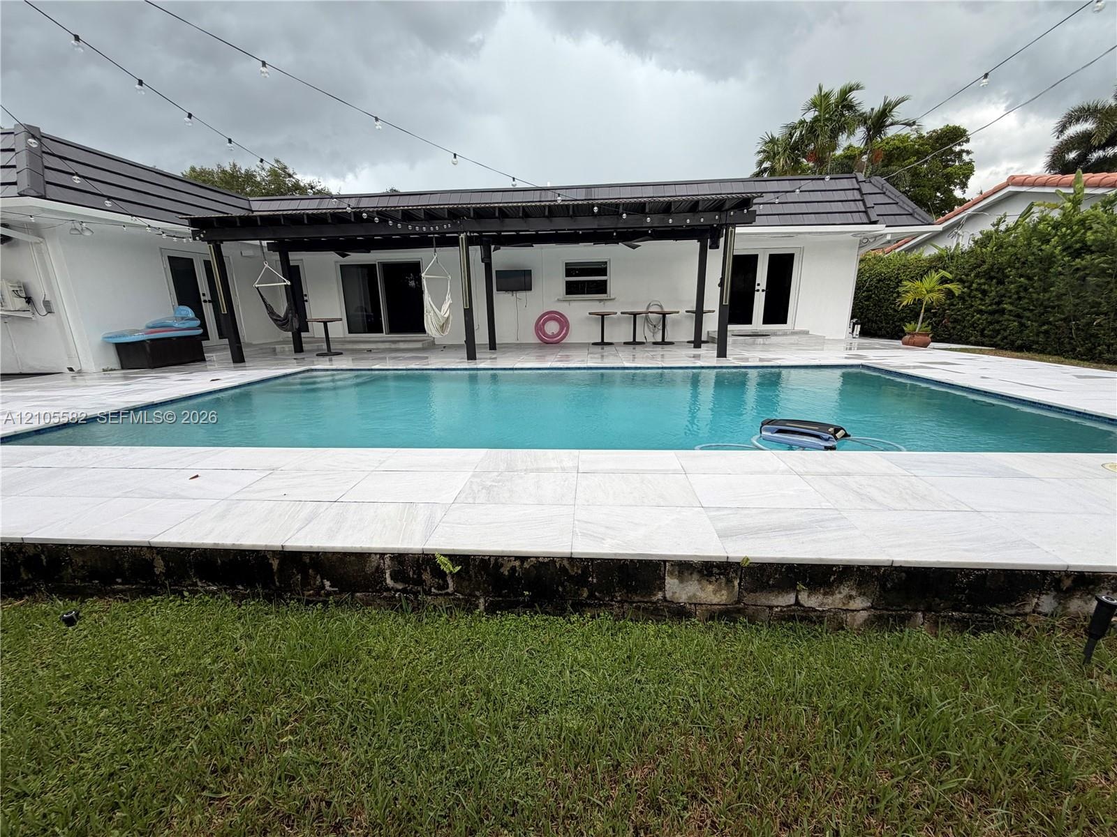 In-ground swimming pool with a surrounding stone tile patio