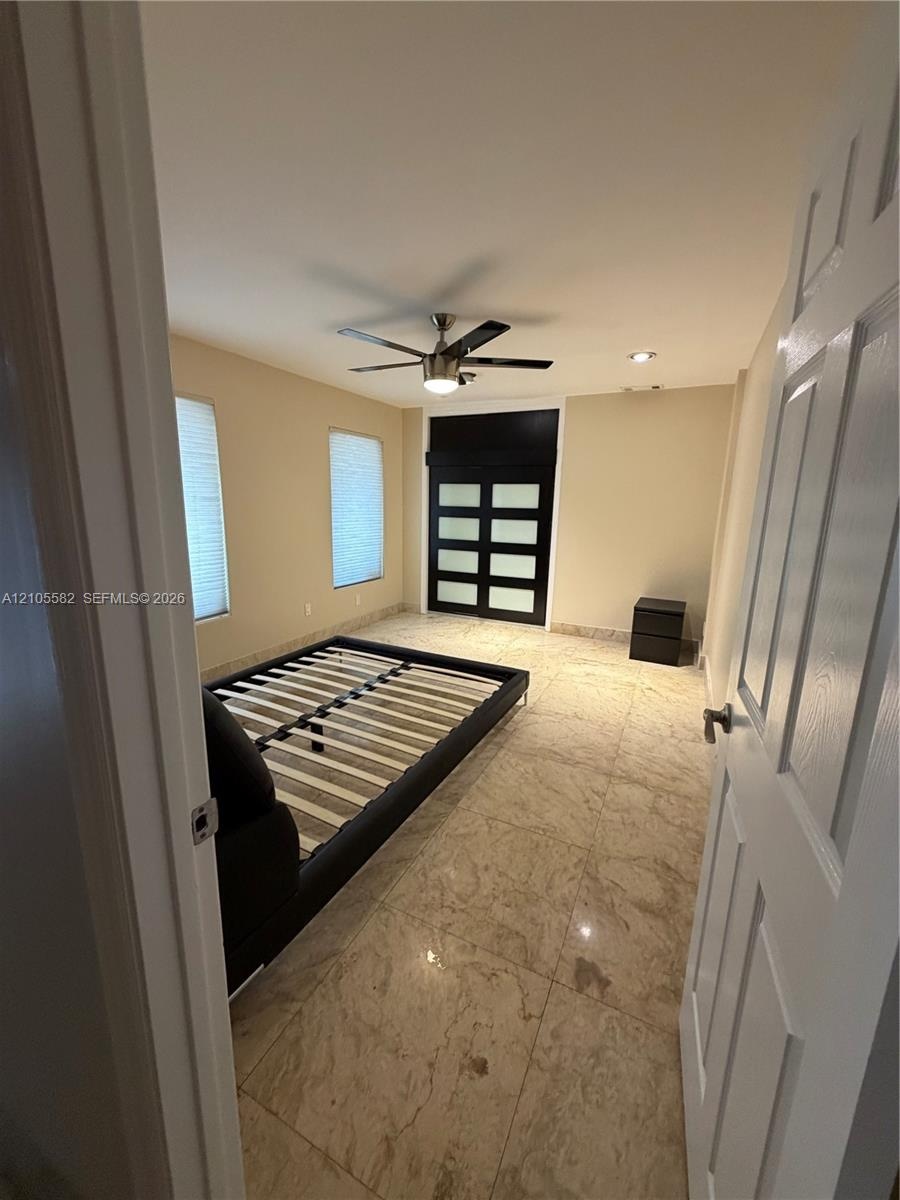 Polished tile flooring, recessed ceiling lighting, ceiling fan with integrated light, and a modern paneled door
