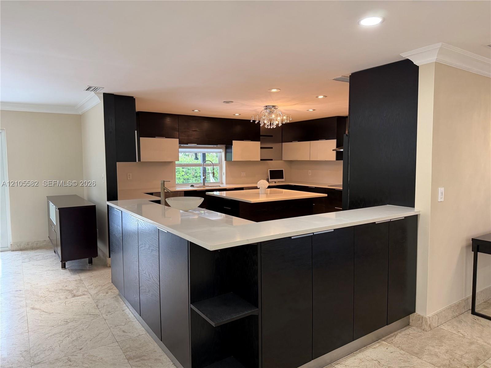 Kitchen featuring dark wood-finish cabinetry, light countertops, and a central island with a vessel sink