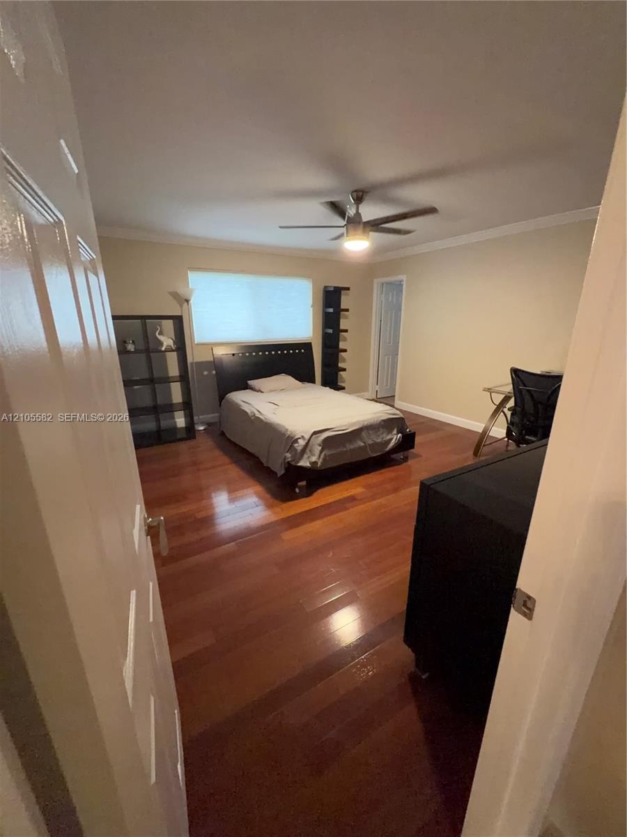 Hardwood flooring, crown molding, ceiling fan with integrated lighting, and neutral wall paint