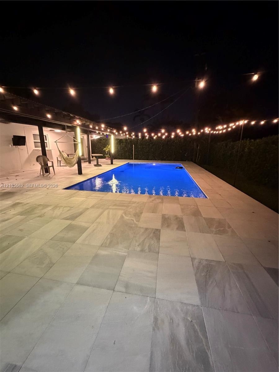 Rectangular swimming pool with perimeter tiling, surrounded by large format tile patio