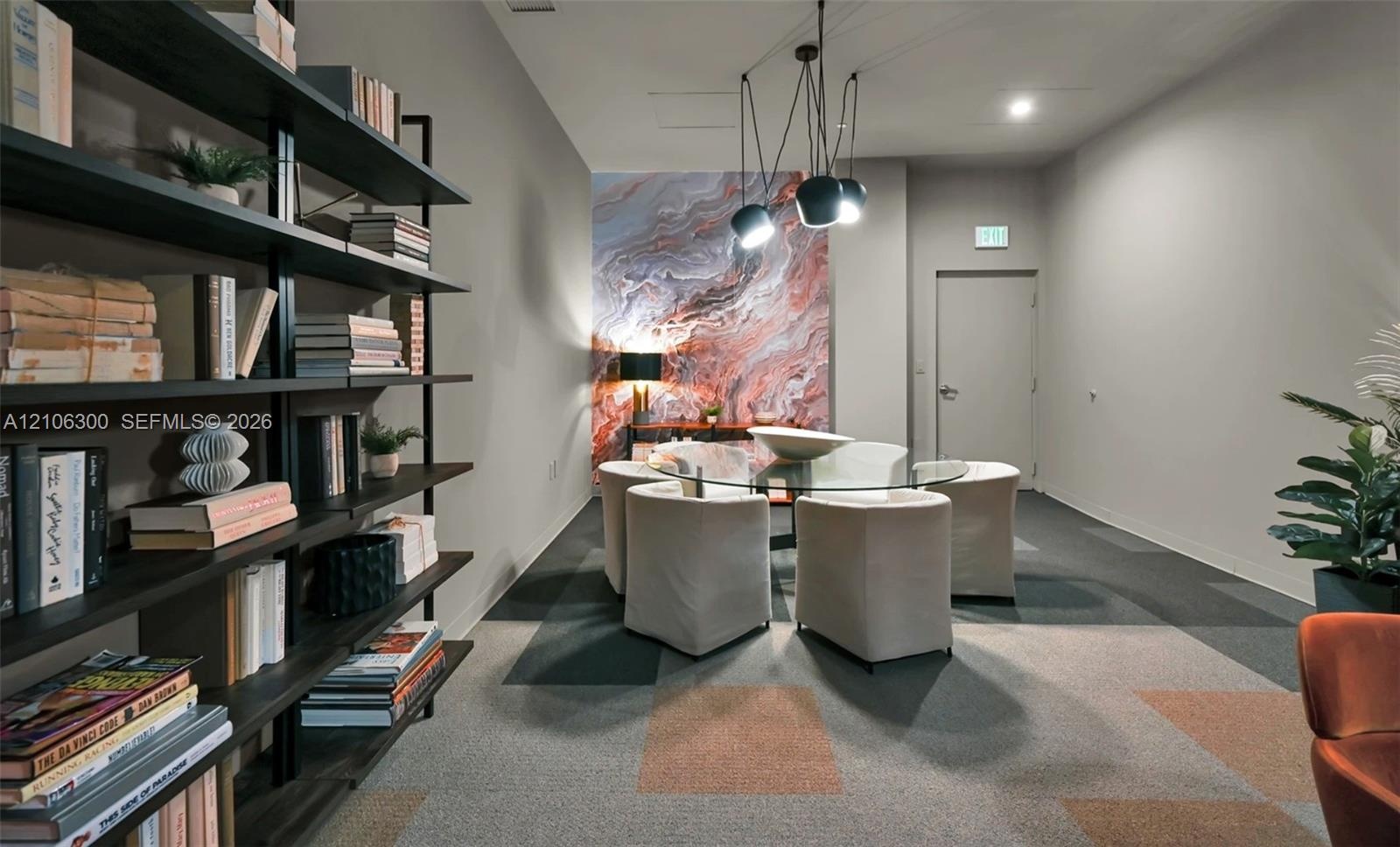 Floor-to-ceiling built-in black metal shelving unit, geometric patterned modular carpeting, decorative marble-finish accent wall, and multi-pendant mo
