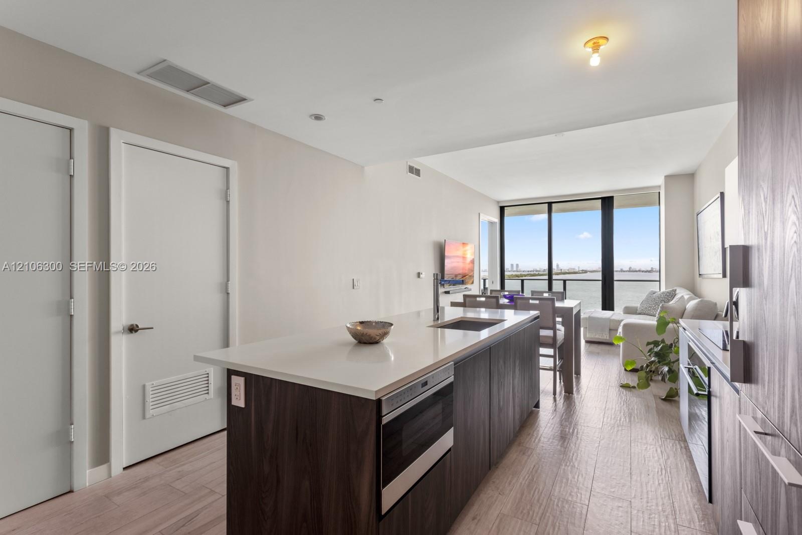 Kitchen featuring a central island with a solid surface countertop, wood-finish cabinetry, built-in microwave, wood-finish flooring, and floor-to-ceil