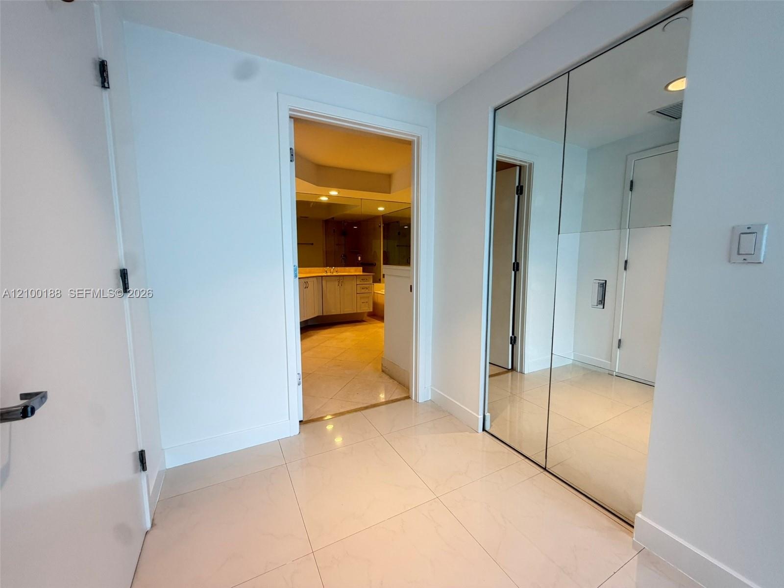 Large-format tile flooring, dual-panel mirrored closet doors, and solid-core interior doors