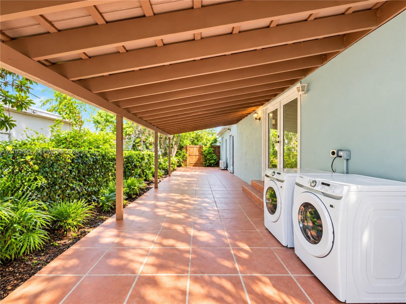 Covered patio featuring terracotta-style tile flooring, wood-beam ceiling structure, and integrated exterior wall lighting