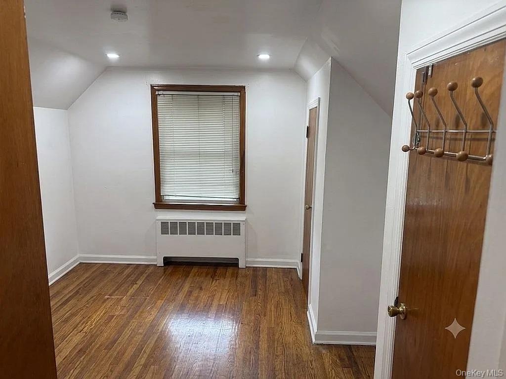 Room featuring wood-finish flooring, recessed lighting, and a single window with wood trim