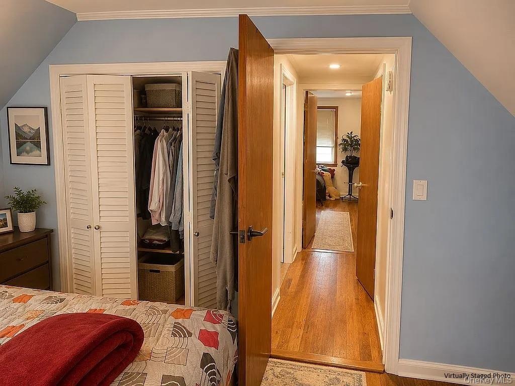Wood-finish flooring, white louvered-door closet with built-in shelving, solid wood interior doors, and crown molding