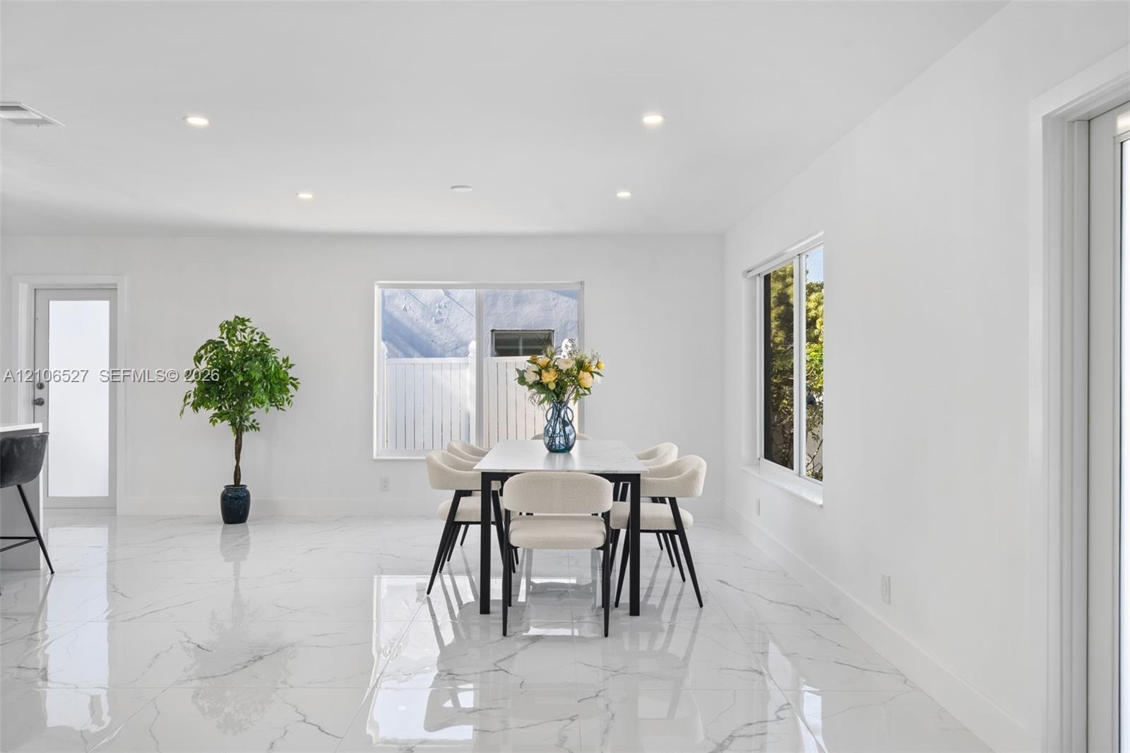 Open-concept interior featuring large-format polished stone-finish floor tiles, recessed ceiling lighting, and multiple windows