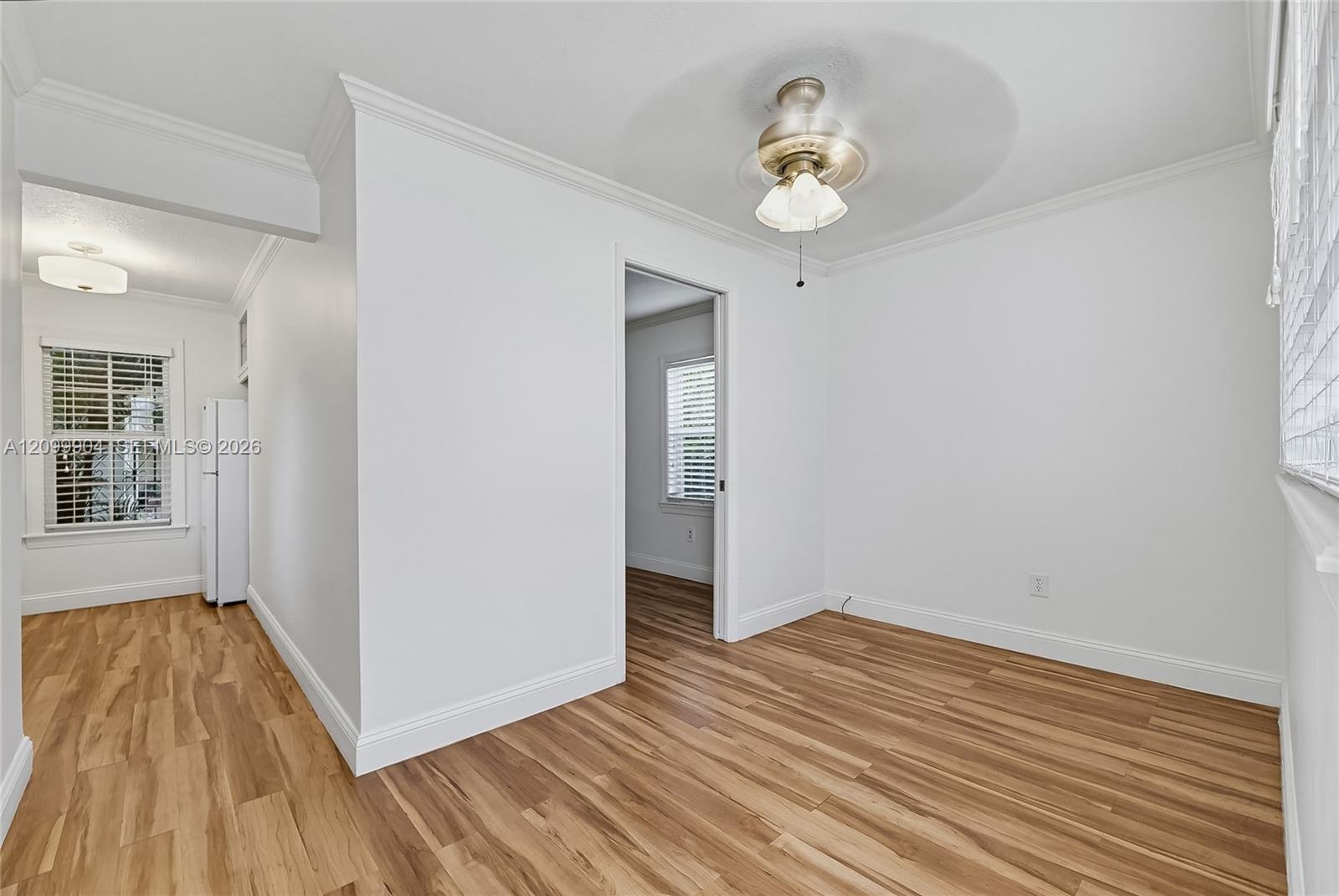 Wood-finish flooring, crown molding, and ceiling fan with integrated light fixture